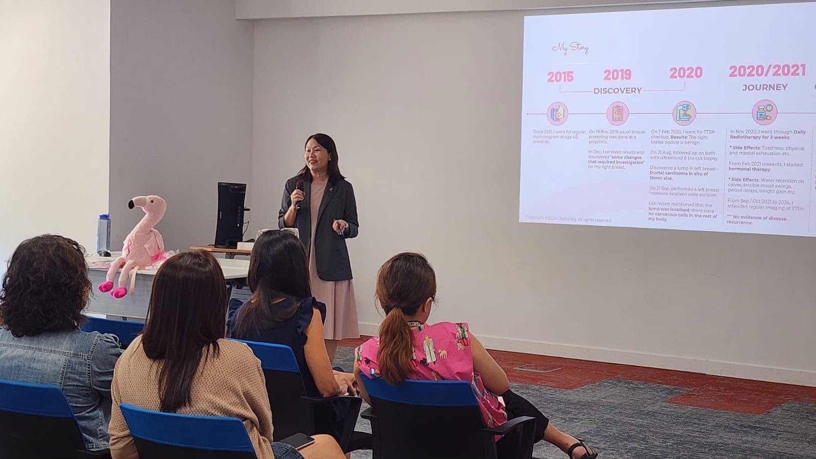 Gladys presenting her “My Story” timeline, from discovery in 2019 to treatment in 2020 and 2021, to a seated audience